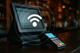 Restaurant POS system with touchscreen terminal and handheld card reader emitting Wi-Fi and EMF signal waves, symbolizing invisible radiation exposure.