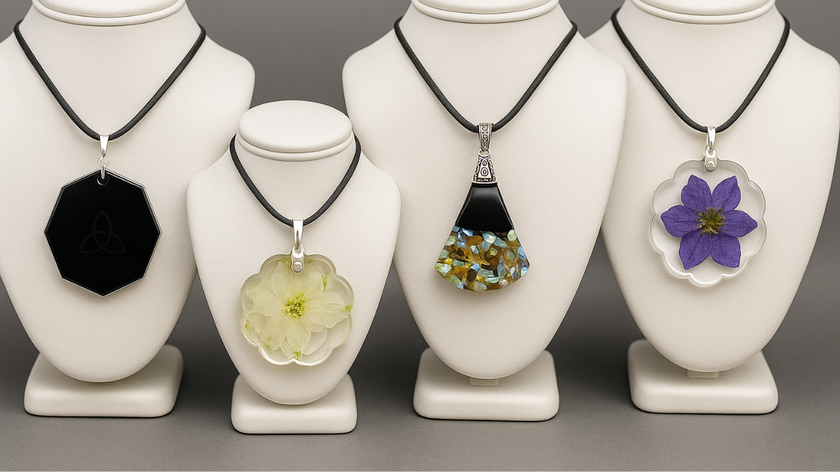 Four EMF harmonizer pendants displayed on necklace stands, featuring black octagon, dried flower resin, gemstone blend, and purple pressed flower EMF pendants in a horizontal layout.