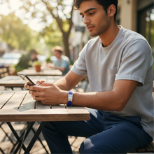 Man wearing blue EMF protection bracelet BodyBand Plus using phone in park