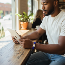 Man wearing blue EMF protection bracelet BodyBand Plus using iPad