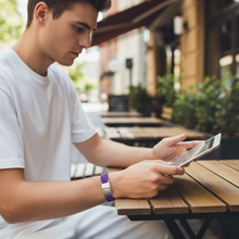 Man wearing purple EMF protection bracelet BodyBand Plus using iPad