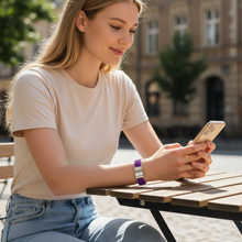 Young woman wearing purple EMF protection bracelet BodyBand Plus using iPhone