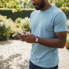 Man wearing purple EMF protection bracelet BodyBand Plus using smartphone