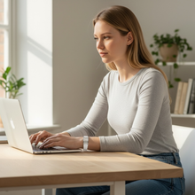 Young woman wearing white EMF protection bracelet BodyBand Plus on MacBook