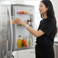 Woman wearing white EMF protection bracelet BodyBand Plus near fridge