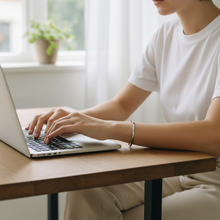 Woman wearing feminine stainless steel EMF protection cuff bracelet on laptop