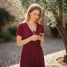 Woman wearing EMF protection necklace classic octagon black pendant using phone