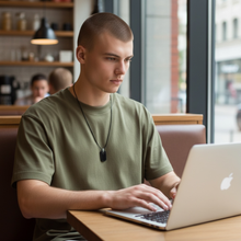 Young man wearing EMF protection necklace dog tag BodyShield perfectly imperfect on MacBook