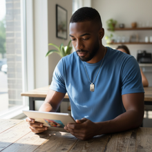 Man wearing stainless steel EMF protection dog tag necklace using iPad