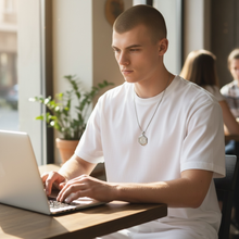 Man wearing stainless steel EMF protection necklace octagon pendant using laptop