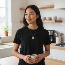 Woman wearing stainless steel EMF protection dog tag necklace drinking coffee