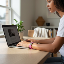 Girl wearing pink EMF protection bracelet BodyBand Plus on laptop