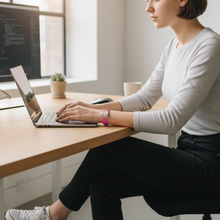 Young woman wearing pink EMF protection bracelet BodyBand Plus working on laptop