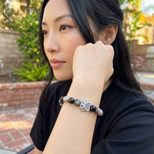 Woman wearing a black EMF Protection Dog Paw Bracelet with silver paw charm and handcrafted black beaded design for everyday wear.