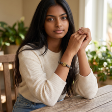Woman wearing black EMF protection bracelet with gold dog paw charm and proprietary resonant frequency technology