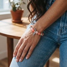 Woman wearing the Blush Pink Angel Wings EMF Protection Bracelet with pink beaded stones and angel wing charm for everyday wear