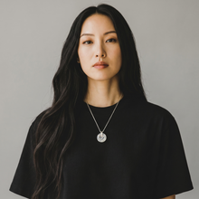 Woman wearing a Clear EMF Protection Button Necklace with stainless steel chain for everyday wearable protection and wellness.