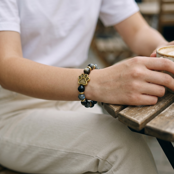 Close-up of black beaded EMF protection bracelet with gold dog paw charm designed for dog lovers and everyday wear