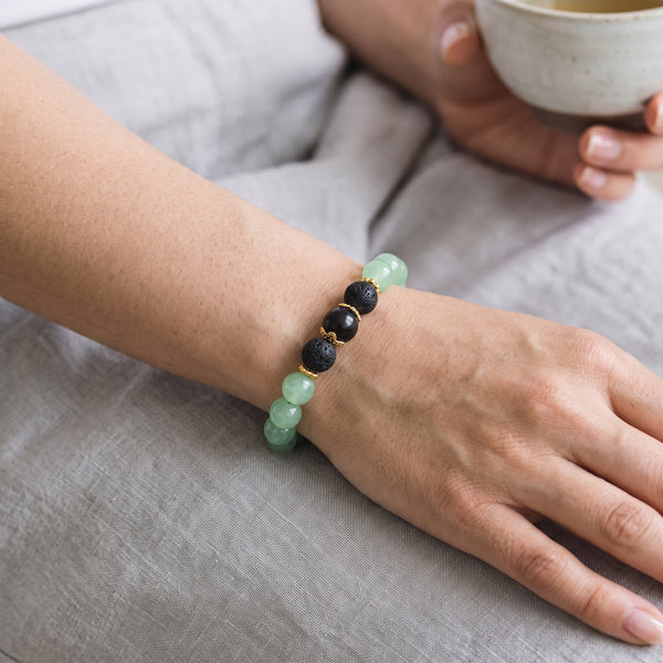 Green Aventurine EMF Protection Beaded Bracelet worn on wrist while holding a cup of tea