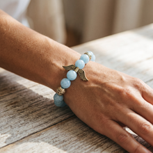Woman wearing the Sky Blue Angel Wings EMF Protection Bracelet with light blue beaded stones and angel wing charm for everyday wear