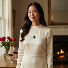 Model wearing large emerald heart EMF protection necklace with silver chain in elegant indoor setting