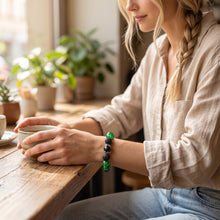 Woman wearing the Malachite EMF Protection Beaded Bracelet at a café table holding a cup