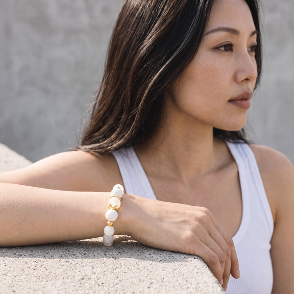 Woman wearing the Moonstone EMF Protection Beaded Bracelet outdoors in a white tank top