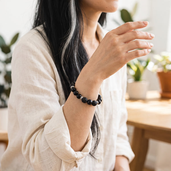 Woman wearing the Obsidian EMF Protection Beaded Bracelet in a cream linen top