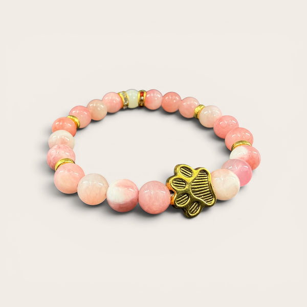 Pink EMF protection bracelet with gold dog paw charm infused with 240+ resonant frequencies for everyday wellness and EMF protection.
