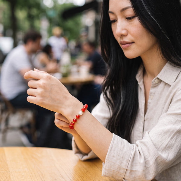 Woman wearing the Red Auspicious EMF Protection Beaded Bracelet at a cafe