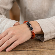 Red Jasper EMF Protection Beaded Bracelet worn on wrist resting on a wooden table