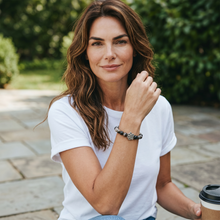 Woman wearing a black beaded EMF Protection Dog Paw Bracelet featuring a silver paw charm and wearable EMF protection technology.